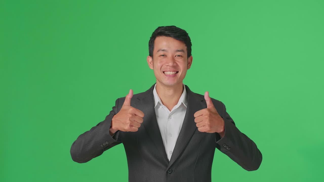 Happy Asian Business Man Showing Thumbs Up Gesture While Standing In The Green Screen Studio