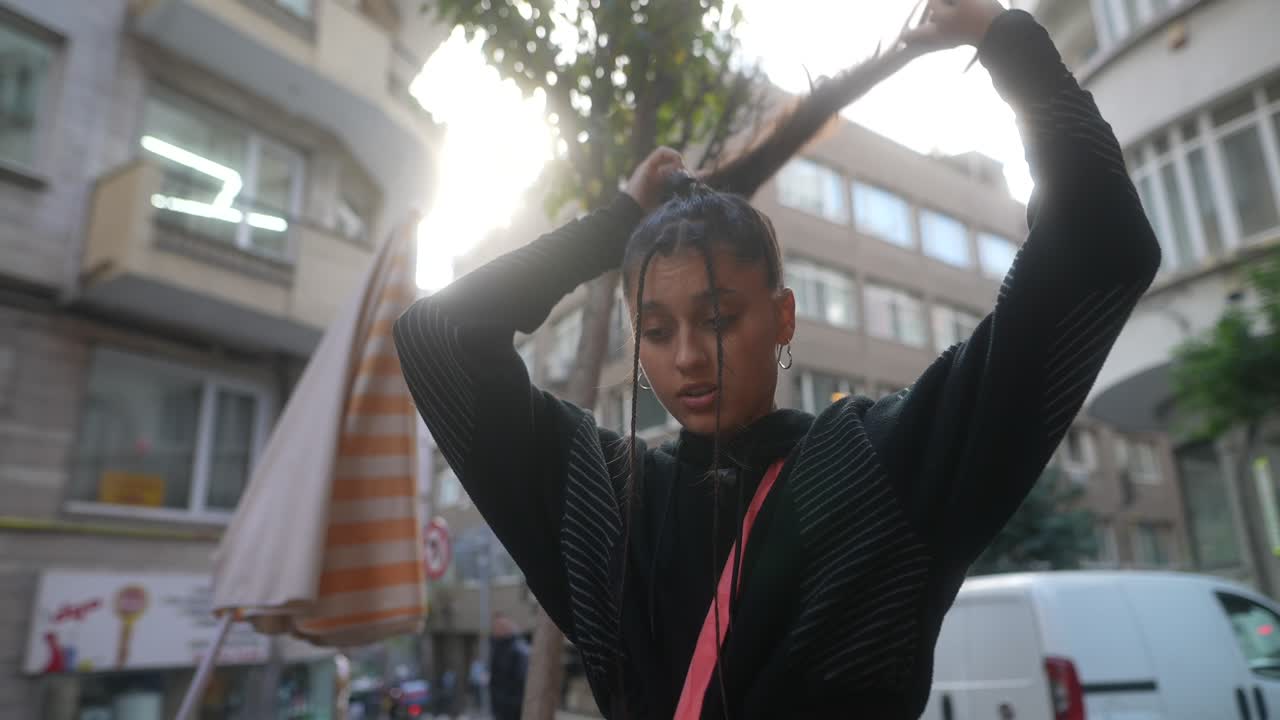 una mujer joven estilizando su cabello en la calle.