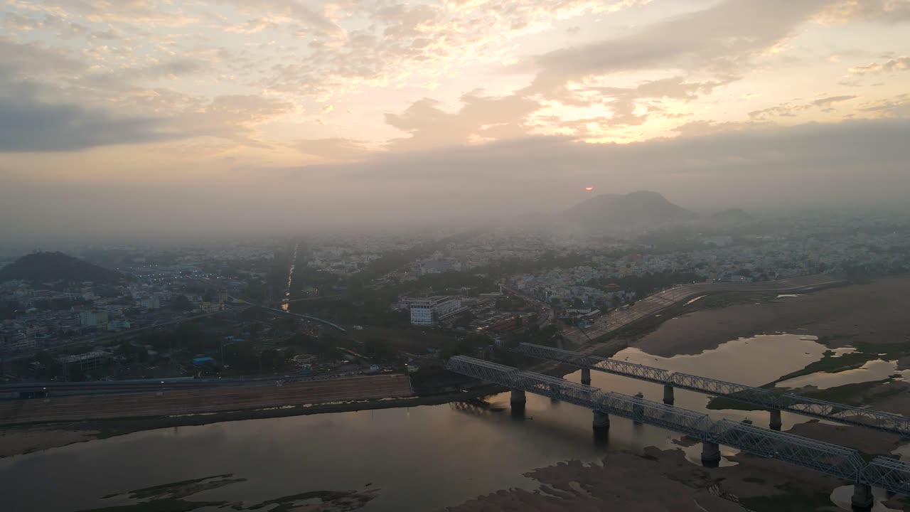 Aerial drone shot capturing Vijayawada city during sunrise, with soft morning light bathing its iconic landmarks.