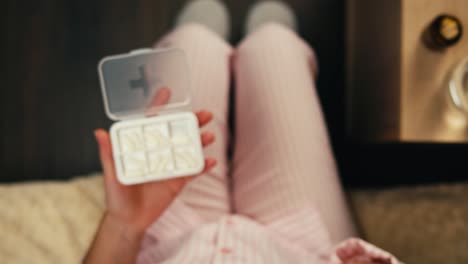 mujer tomando pastillas en la cama