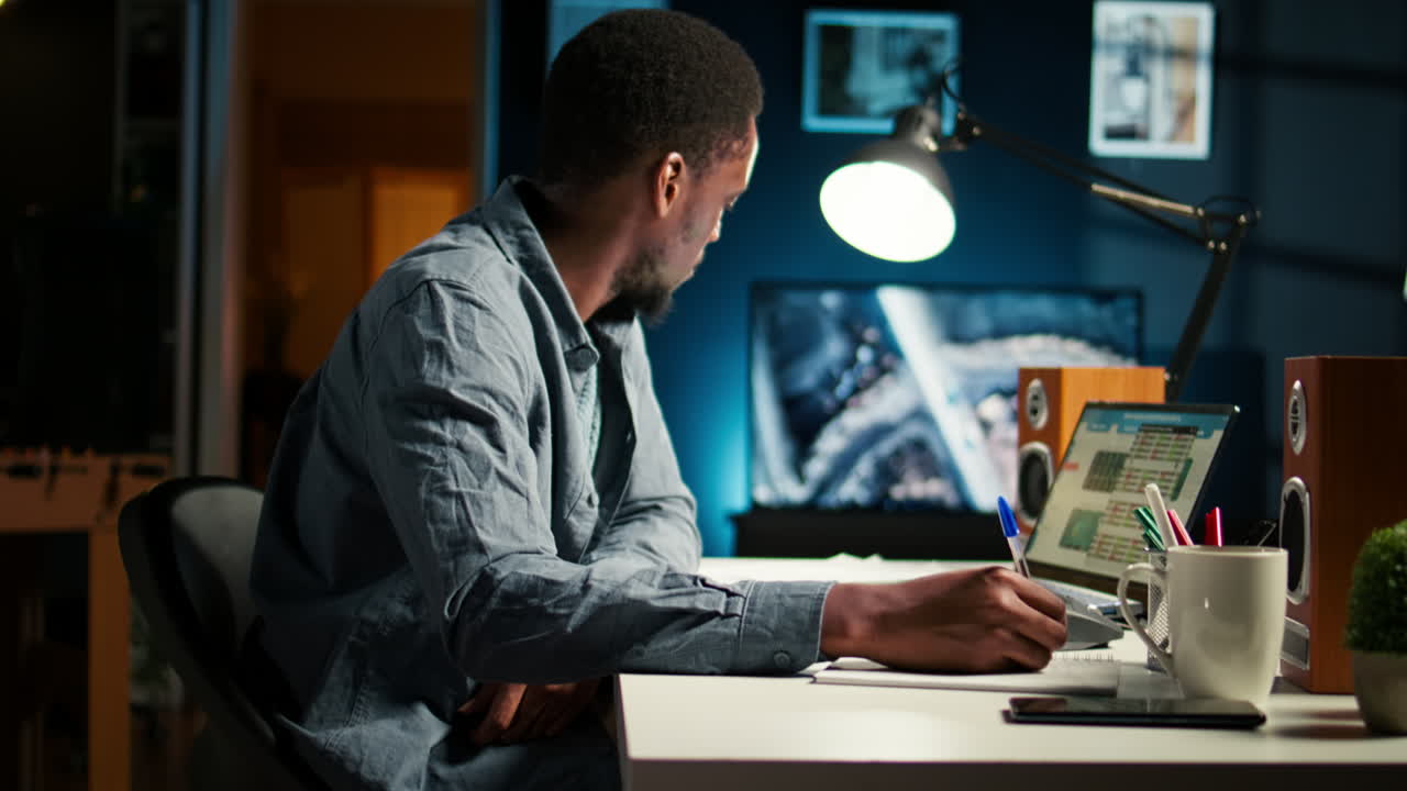 African American freelancer working from home writing notes and researching