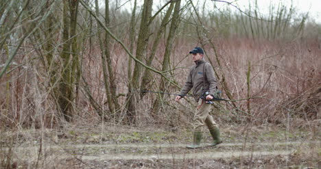 hombre con caña de pescar caminando entre árboles desnudos 6