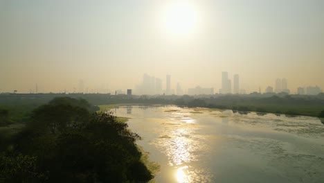 Mumbai-skyline-covered-in-smog,-extreme-air-pollution-India,-drone-aerial-establishment-shot,-view-from-water-lake