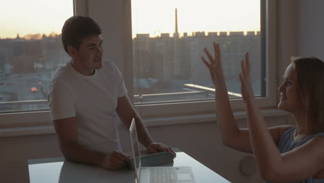 Young-couple-having-a-vivid-talk-using-electronics