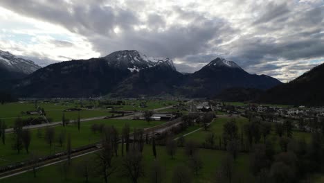 aerial establishing above leafless trees in rows on farm fields to base of mountains in walensee switzerland