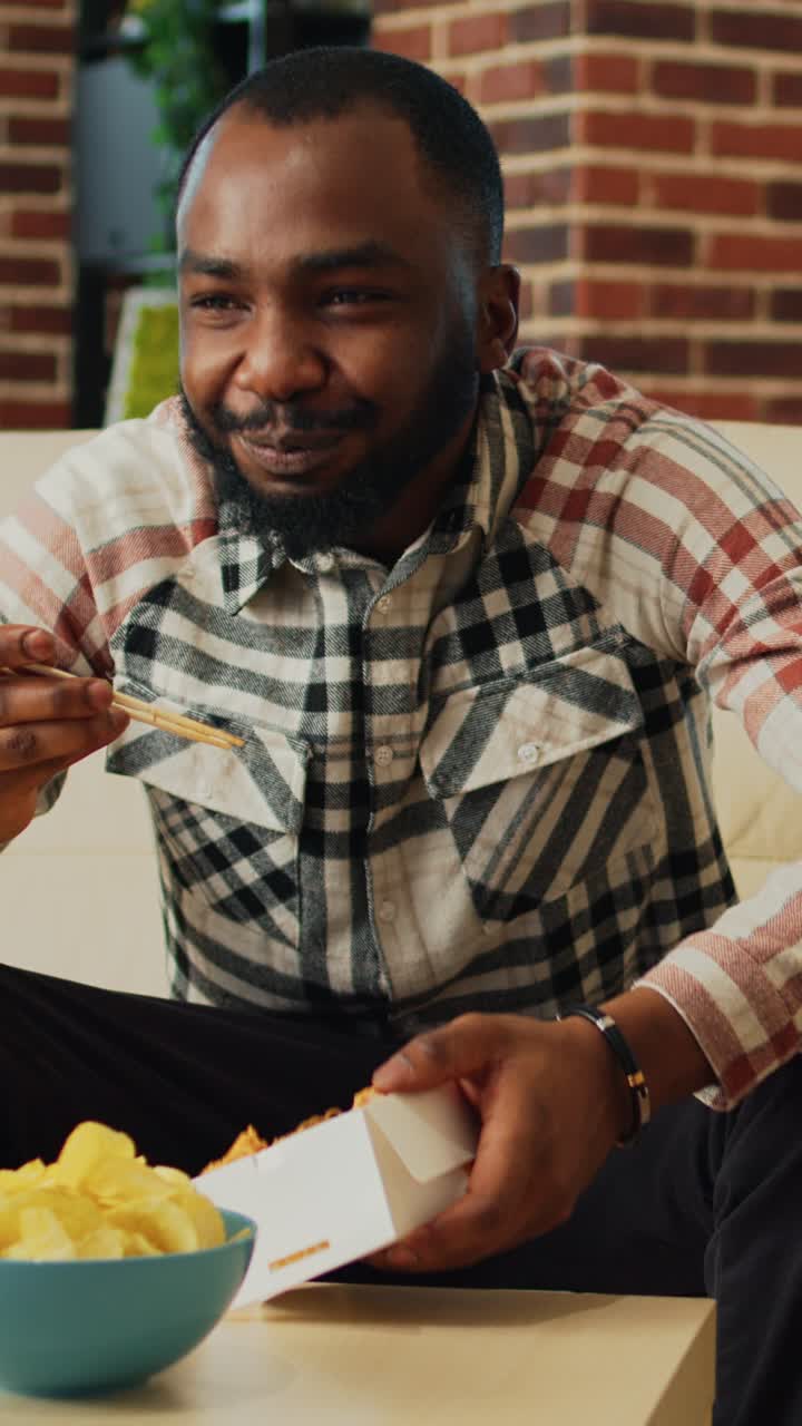 Vertical video: Happy adult serving noodles from box with chopsticks