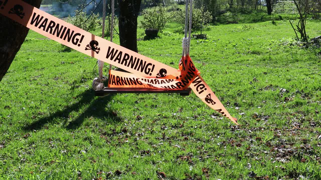 Warning sign on ribbon on swing