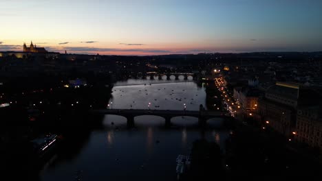 a stunning drone capture of prague's passage canal, illuminated bridge, and city skyline at sunset, transitioning into a magical night-time view.