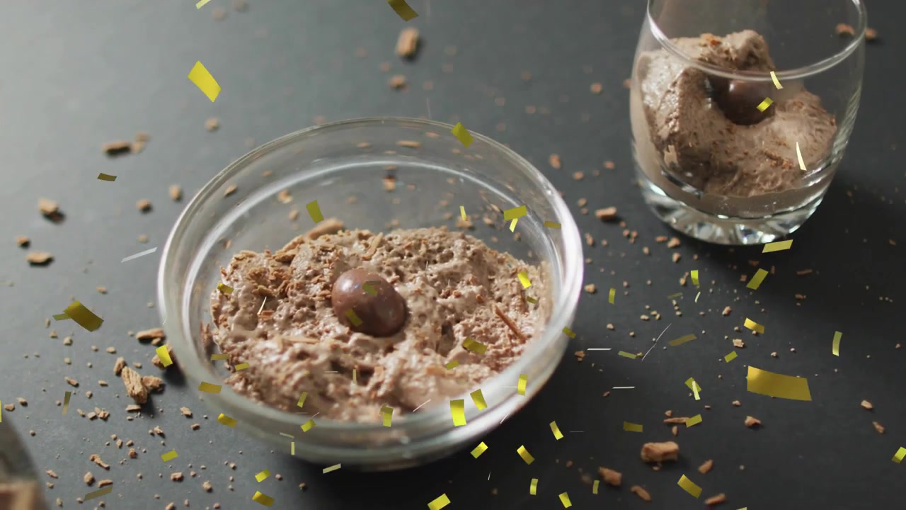 Gold confetti falling from above, glass bowl catching pieces, decorating mousse for party