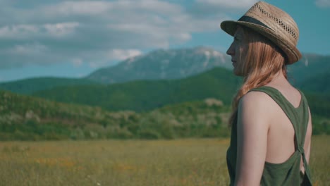 woman with hat in sunny mountain field