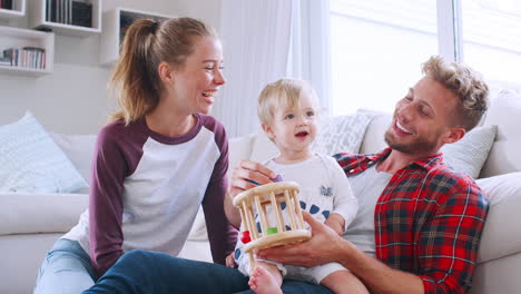 Una-Pareja-Joven-Sentada-En-El-Suelo-Jugando-Con-Su-Hija-En-Casa