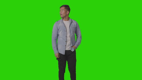 Portrait-Of-Casually-Dressed-Smiling-Young-Man-Looking-Around-Against-Green-Screen-1