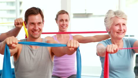 Fitness-group-sitting-on-exercise-balls-stretching-resistance-bands