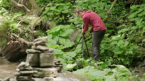 fotógrafo poniendo su cámara en su trípode y preparándose para capturar una foto en la naturaleza