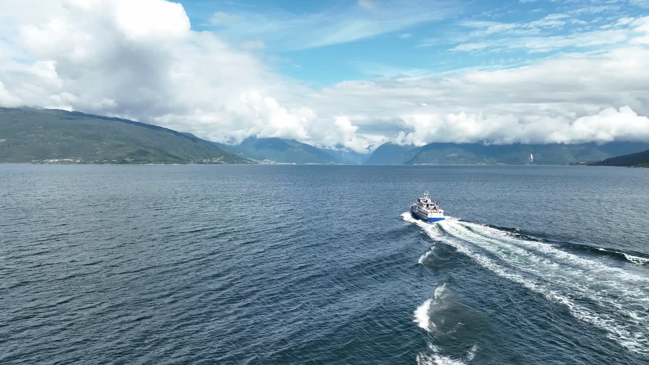 seguimiento aéreo de un barco turístico por detrás en el sognefjorden en noruega durante el verano - turistas sentados en la cubierta de popa durante un viaje de vacaciones a balestrand y fjaerland - 60 fps