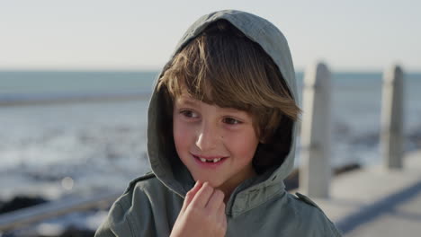 close up portrait playful little boy smiling cheerful enjoying vacation on beautiful sunny seaside wearing warm jacket slow motion