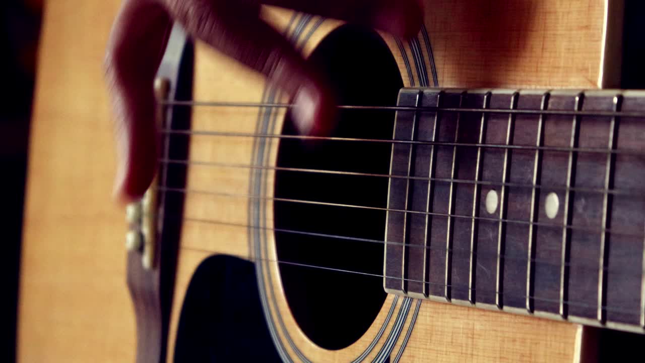 Närbild av en kvinnas hand som spelar gitarr.
