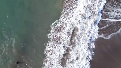 aerial view of person in water being pushed by waves