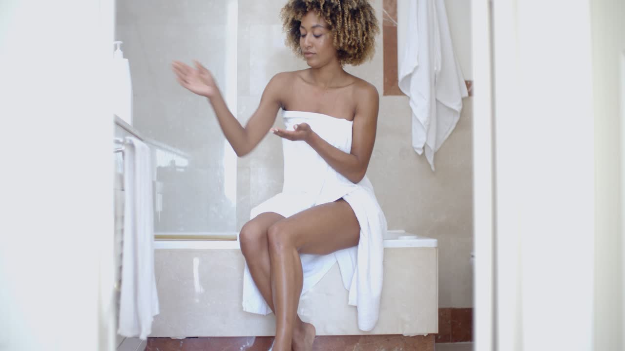 Donna che applica la lozione per il corpo in bagno