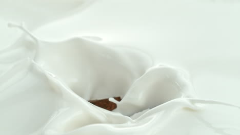 coconut chunks falling into creamy milk making swirly splashes in macro and slow motion