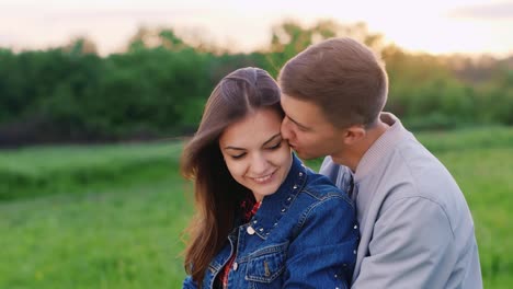 una pareja enamorada descansando en el parque sentada en un abrazo en el césped hablando de video hd