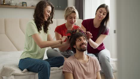 Three-women-having-fun,-creating-new-hairstyle-to-their-male-gay-friend