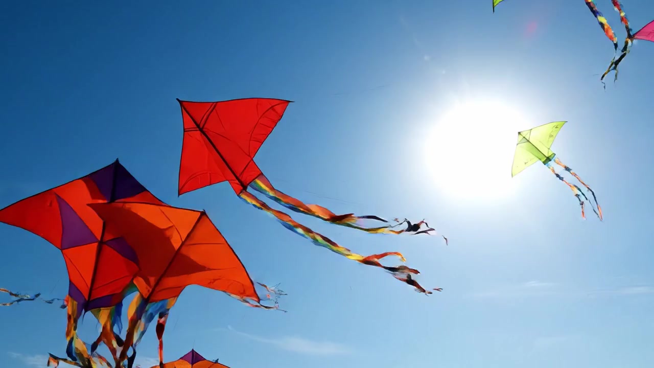 Uma exibição colorida de pipas voando alto contra um céu azul claro com luz solar brilhante ao fundo, capturando a alegria e a liberdade de voar.