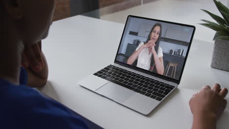 mujer afroamericana hablando en videollamada en computadora portátil con una colega de oficina en casa