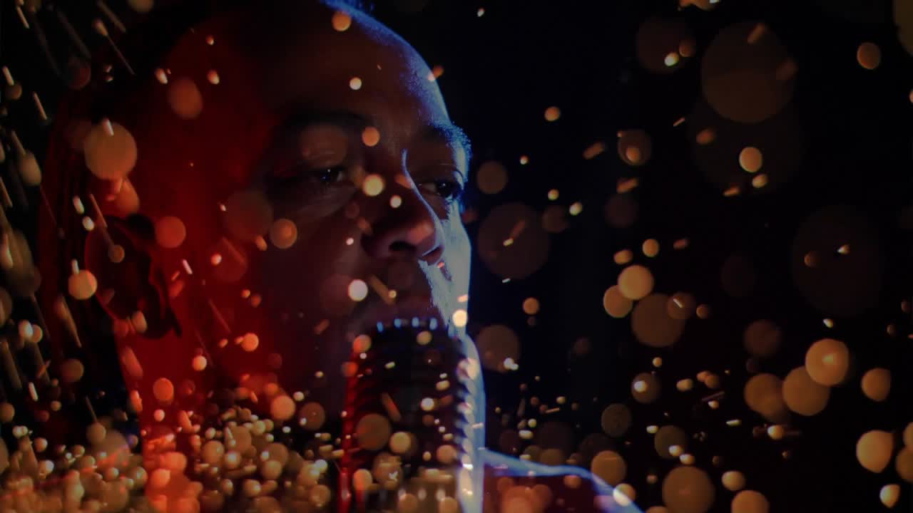 As glowing orange particles swirling, male singer leaning into microphone, singing line for music