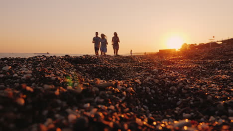 A-Family-With-A-Child-Jogs-Along-The-Surf-Line-To-The-Sea-At-Sunset