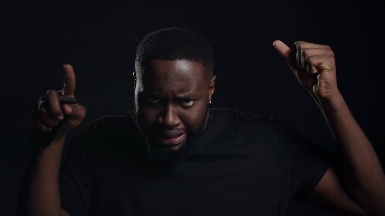 дружелюбный парень делает движения на черном фоне. человек делает жесты в помещении