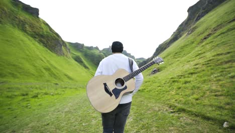 A-man-walking-away-from-the-camera-with-a-guitar-on-his-back