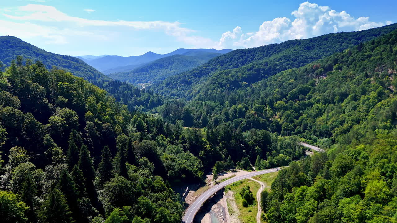 Lush green mountains and winding road surrounded by trees. A scenic view of green mountains with a winding road and lush forests under a clear blue sky