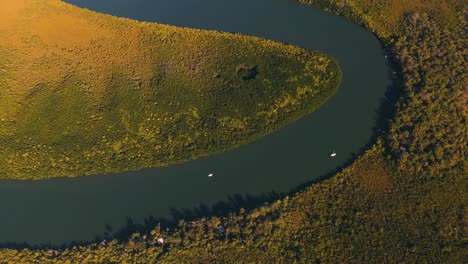 River-sunset-landscape-with-boats-on-water,-aerial-tilt-dolly-reveal