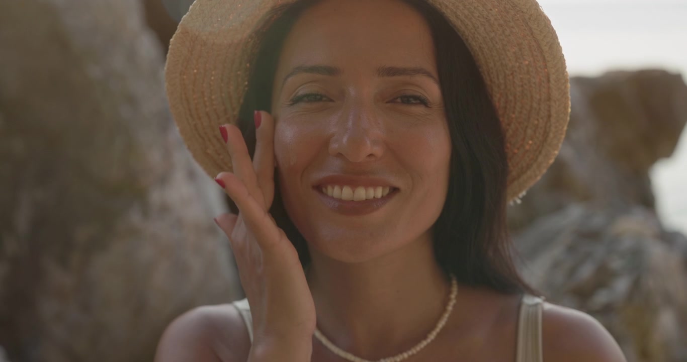 Smiling Woman Applying Sunscreen to Her Face Outdoors