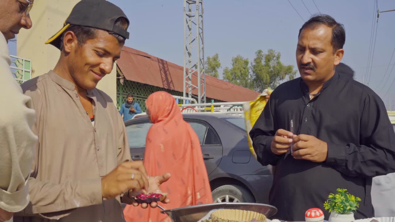 Close-up view of a street food vendor in Islamabad, Pakistan, engaging with customers and offering delicious options from his stall outside the bustling market.