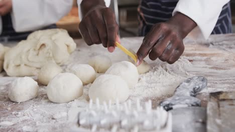 Diverse-bakers-working-in-bakery-kitchen,-cutting-dough-in-slow-motion