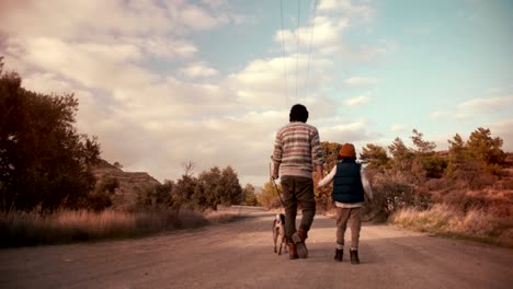 young father and son walking with dog on nature footpath