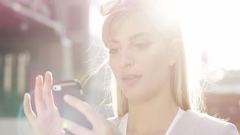 Schöne-Blonde-Frau-Nutzt-Smartphone-Sonneneruptions-Sonnenlicht-Energiekonzept