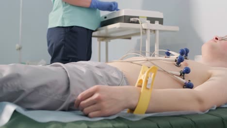 cardiac examination in a hospital with a professional cardiograph. the patient lies on a bed with connected sensors.