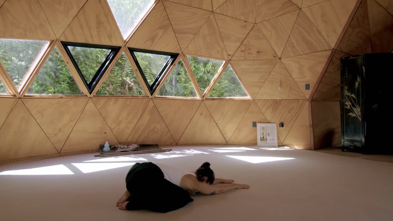 Childs pose relaxing back of Latina woman practicing yoga in a peaceful outdoor studio, focusing on mindfulness and calm movements