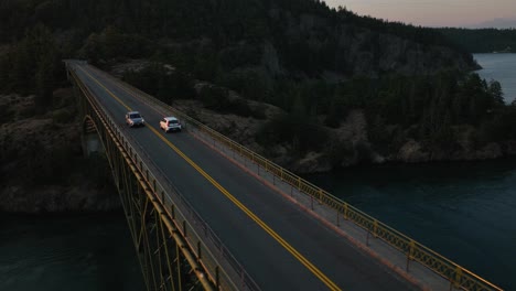 Drohnenaufnahme-Von-Autos,-Die-Bei-Sonnenaufgang-über-Die-Brücke-Des-Deception-Pass-State-Park-Fahren