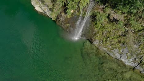 Hermosa-Cascada-En-El-Hermoso-Río-Pelorus-Azul-Claro-Prístino,-Nueva-Zelanda-Con-Rocas-Y-Exuberante-Bosque-Nativo-En-El-Fondo---Drone-Aéreo