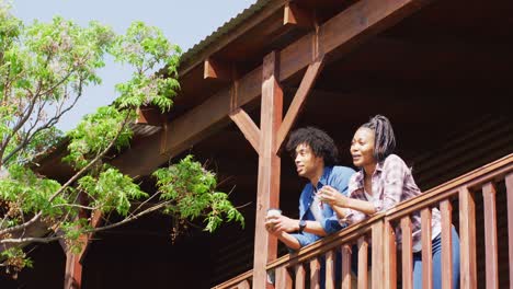 happy african american couple drinking coffee in log cabin, slow motion