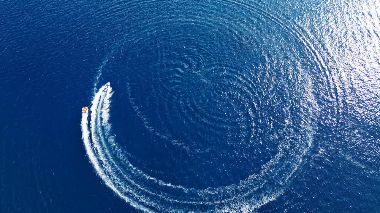 Aerial view of a speedboat drawing a perfect circle on a deep blue water surface. Drone flying over. Croatia