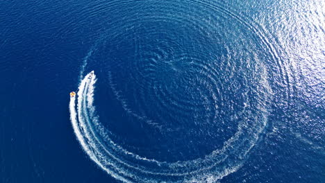 aerial view of a speedboat drawing a perfect circle on a deep blue water surface. drone flying over. croatia