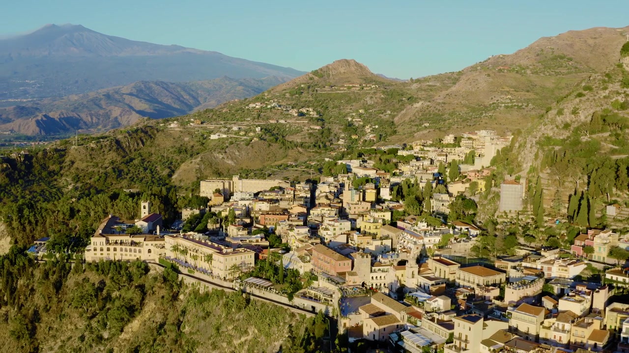 Luftfoto af den italienske by Taormina om morgenen med Etna i baggrunden. Landsby med udsigt til en vulkan. Populært rejsemål på Sicilien