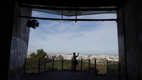 woman holding a phone with lisbon in the background