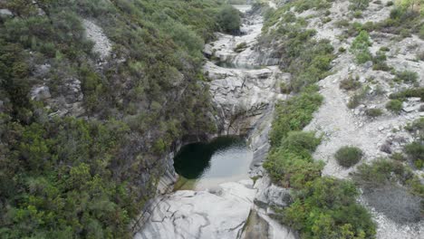 Aerial-view-of-a-tiny-heart-shaped-lake-hidden-between-the-rocks-of-National-Park-Peneda-Gerês,-Portugal