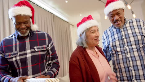 Felices-Y-Diversos-Amigos-Mayores-Vestidos-Con-Traje-De-Santa-Y-Sombreros-Navideños-Intercambiando-Regalos,-Cámara-Lenta